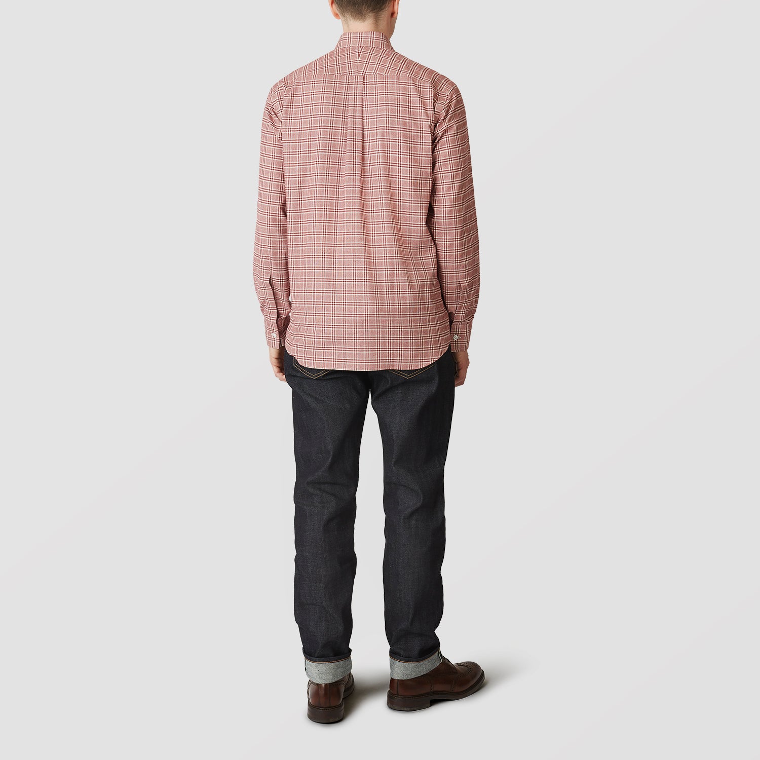 View 2 of product A person in a Turnbull & Asser Red Check Weekend Fit Shirt with a Derby collar and 1-button cuffs, paired with dark cuffed jeans and brown shoes, stands against a plain light background for an ideal winter layered style.