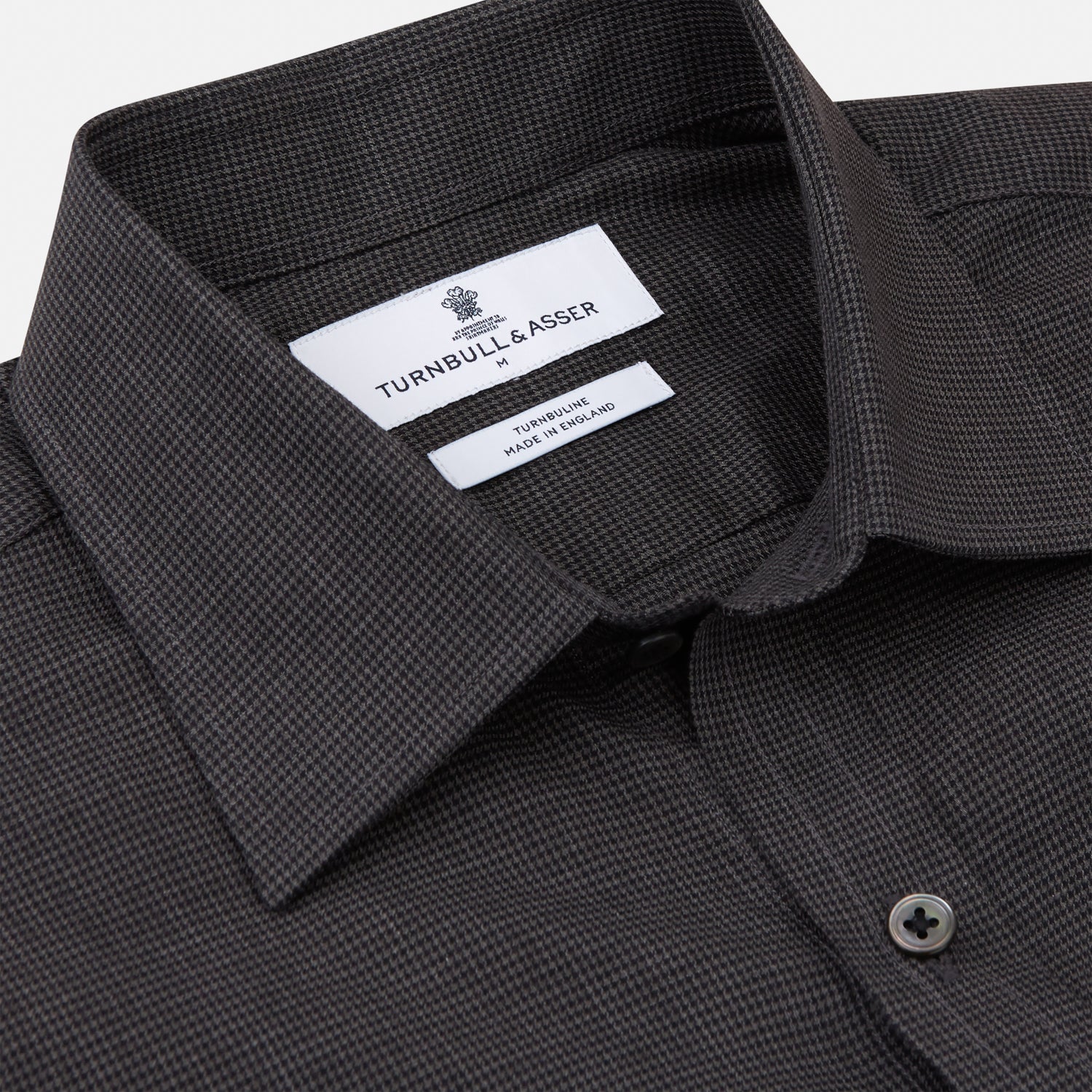 View 3 of product A man with short hair wears the Turnbull & Asser Black Check Weekend Fit Flannel Shirt with Derby Collar and 1-Button Cuffs, paired with light pants, against a plain background—ideal for a smart-casual weekend look.