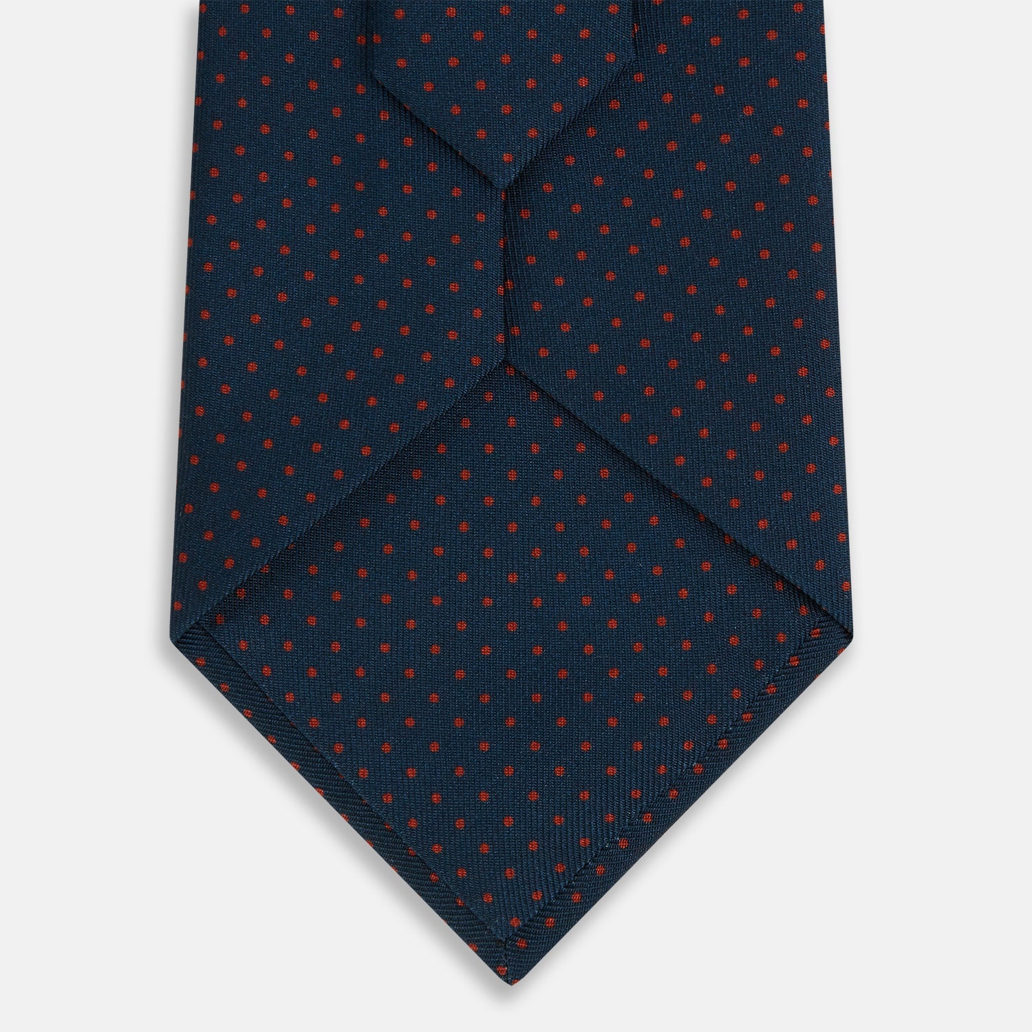 View 3 of product The Turnbull & Asser Navy and Red Polka Dot Silk Tie, rolled neatly on a light background, highlights classic British craftsmanship with its refined pattern.