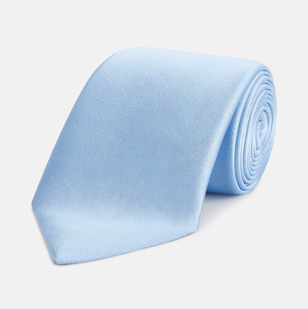 The Turnbull & Asser SATIN RIVER TIE, a neatly rolled light blue silk accessory with a smooth matte finish, is displayed against a plain white background.