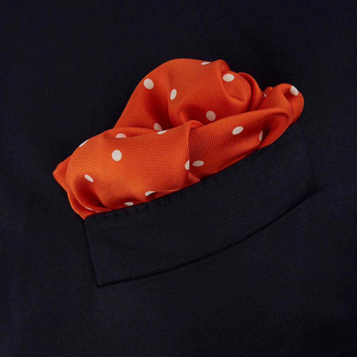 View 4 of product The Orange Spot Silk Pocket Square by Turnbull & Asser features evenly spaced white polka dots and the brand’s name in one corner, making this dapper accessory a standout addition to any outfit.