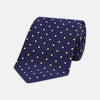 View 1 of product The Turnbull & Asser Navy Spot Woven Herringbone Silk Tie features a navy blue base with evenly spaced yellow polka dots, making it an essential accessory for smart attire. Displayed rolled on a white background.