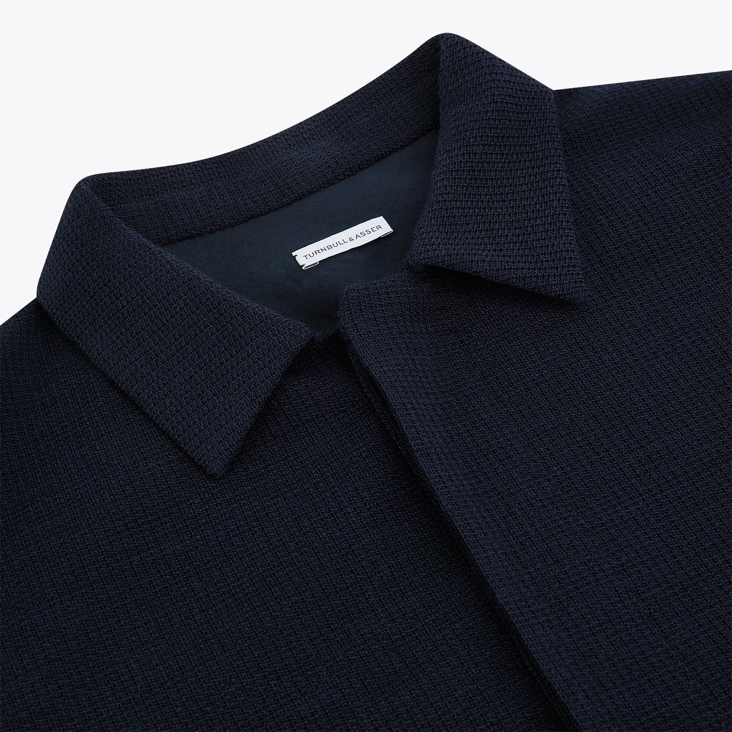 View 2 of product The Turnbull & Asser Navy Greenwich Knitted Overshirt, made from Italian wool with a collar, two front flap pockets, and a hidden button placket, is shown laid flat on a white background.