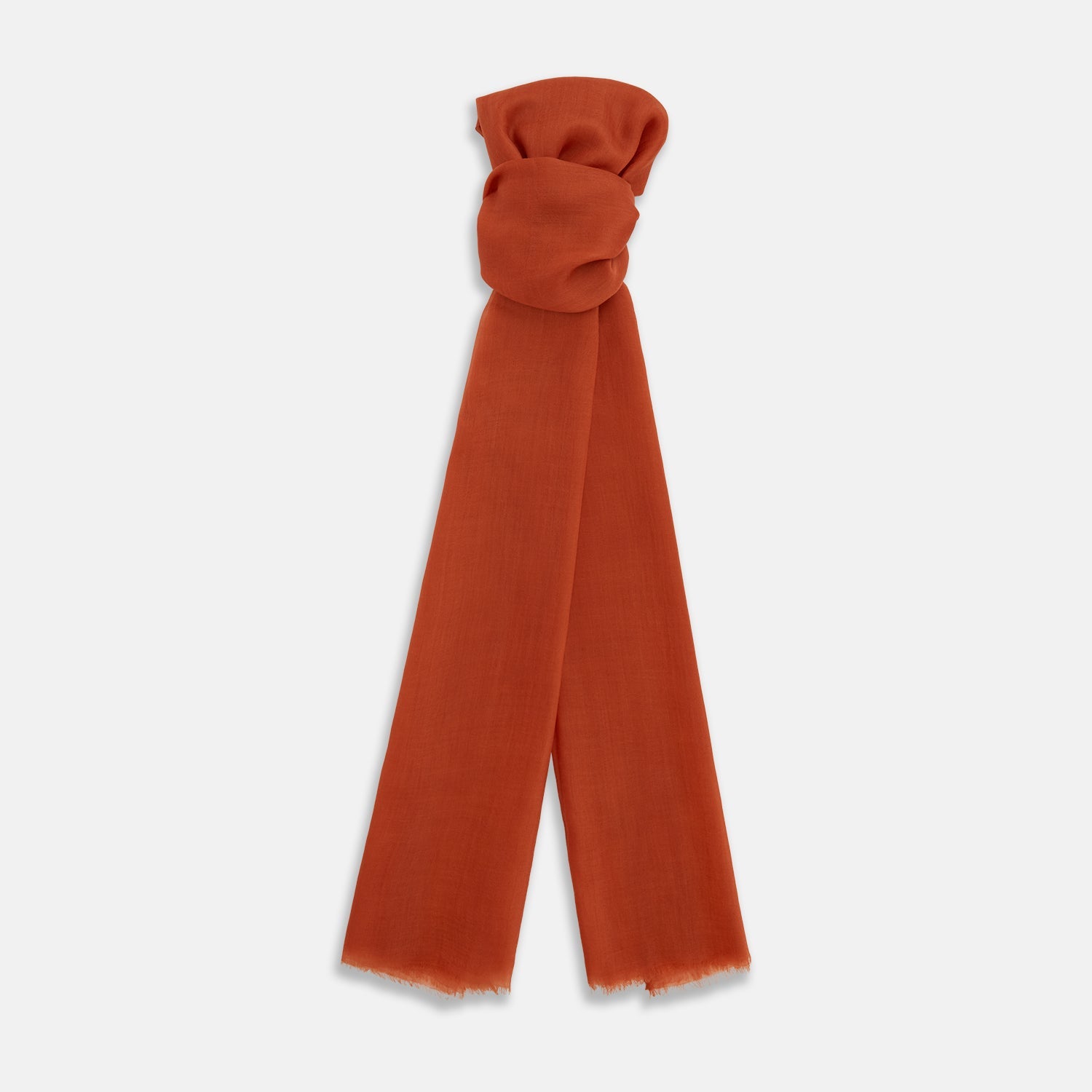 View 1 of product The Rust Cashmere Scarf by Turnbull & Asser is hand-dyed in rust-orange, made from lightweight fabric, tied loosely at the top with both ends hanging down, and finished with subtle frayed edges against a plain white background.