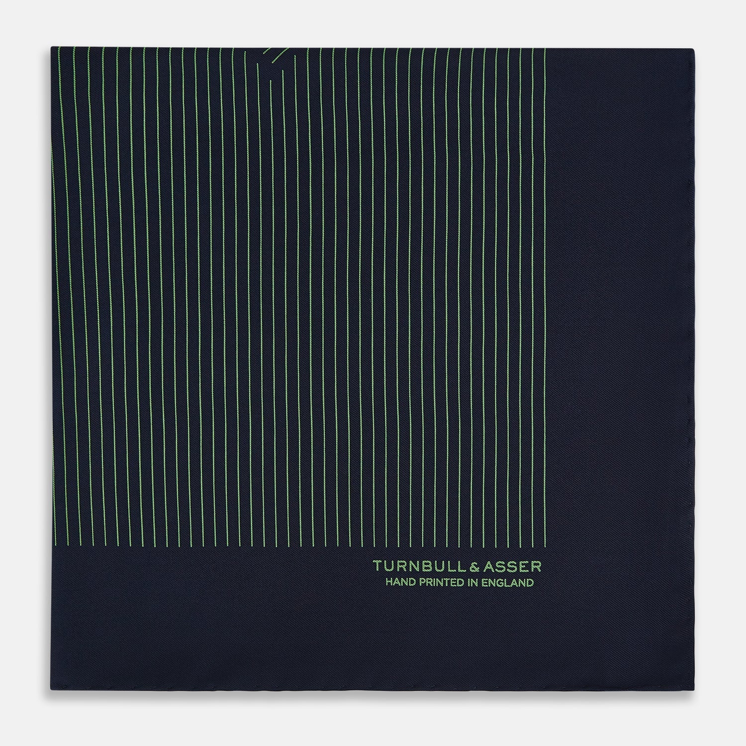 View 4 of product The Navy and Fern Green Stripe Silk Pocket Square by Turnbull & Asser features green vertical and diagonal stripes, hand-rolled edges, and "TURNBULL & ASSER HAND PRINTED IN ENGLAND" printed in one corner.