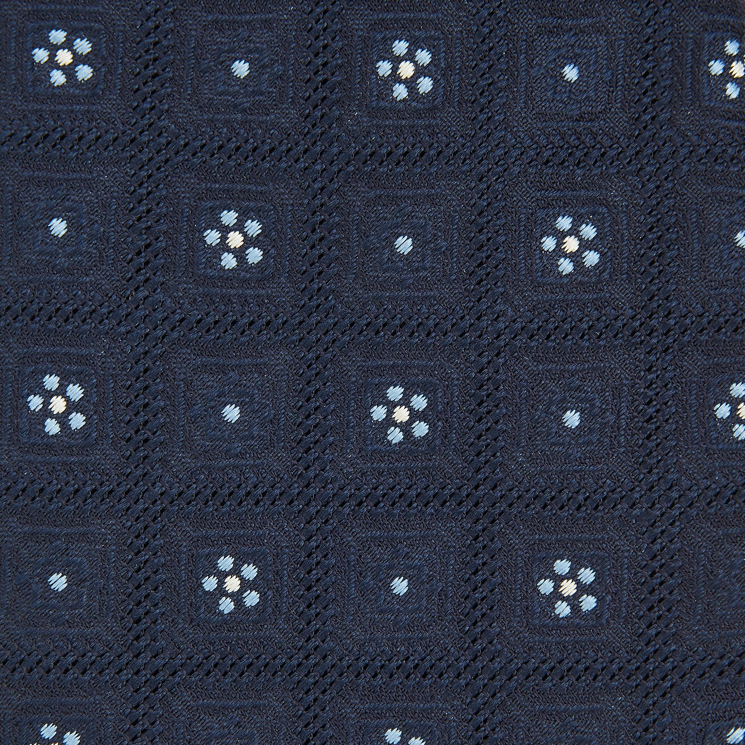 View 3 of product The Turnbull & Asser Jacquard Silk Circle Tie showcases a textured navy blue design with small white and light blue floral motifs—an essential accessory for refined attire.