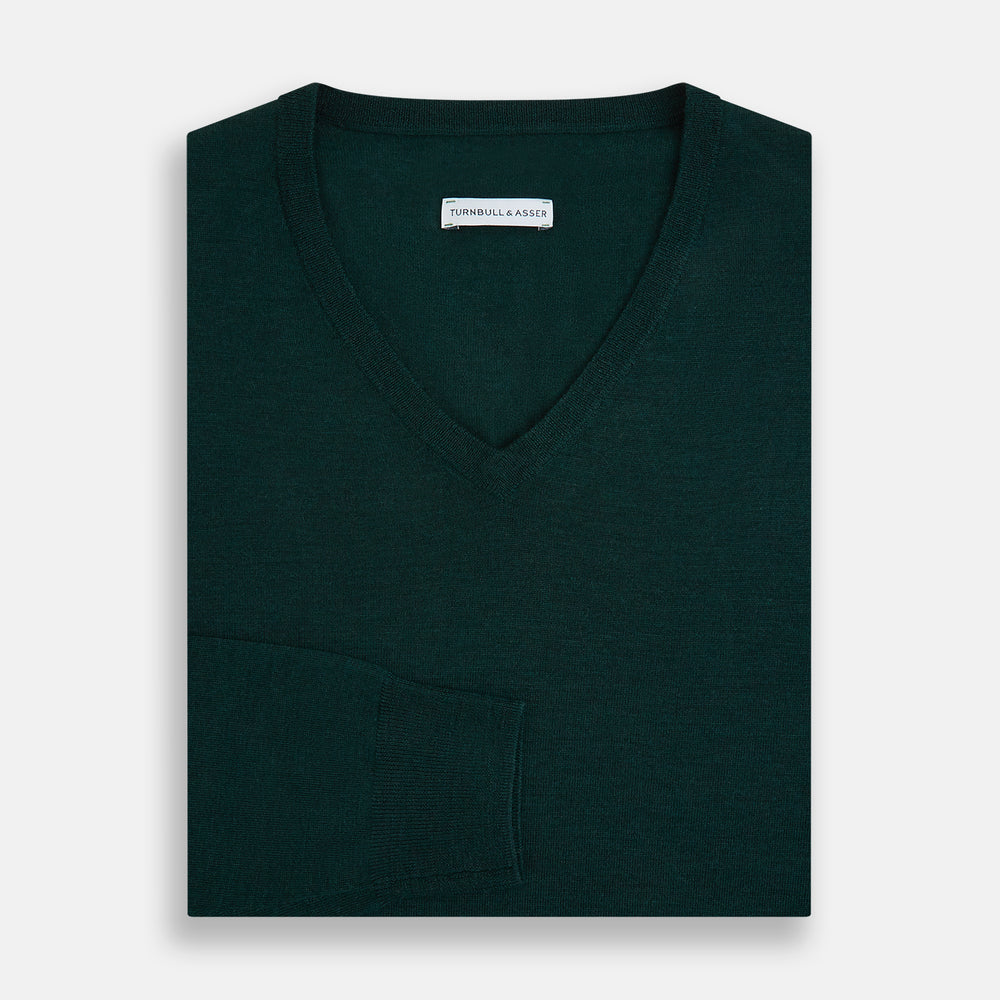 The Turnbull & Asser Petrol Green Merino V-Neck Jumper features long sleeves and ribbed cuffs and hem—an essential knitwear piece, shown against a white background.