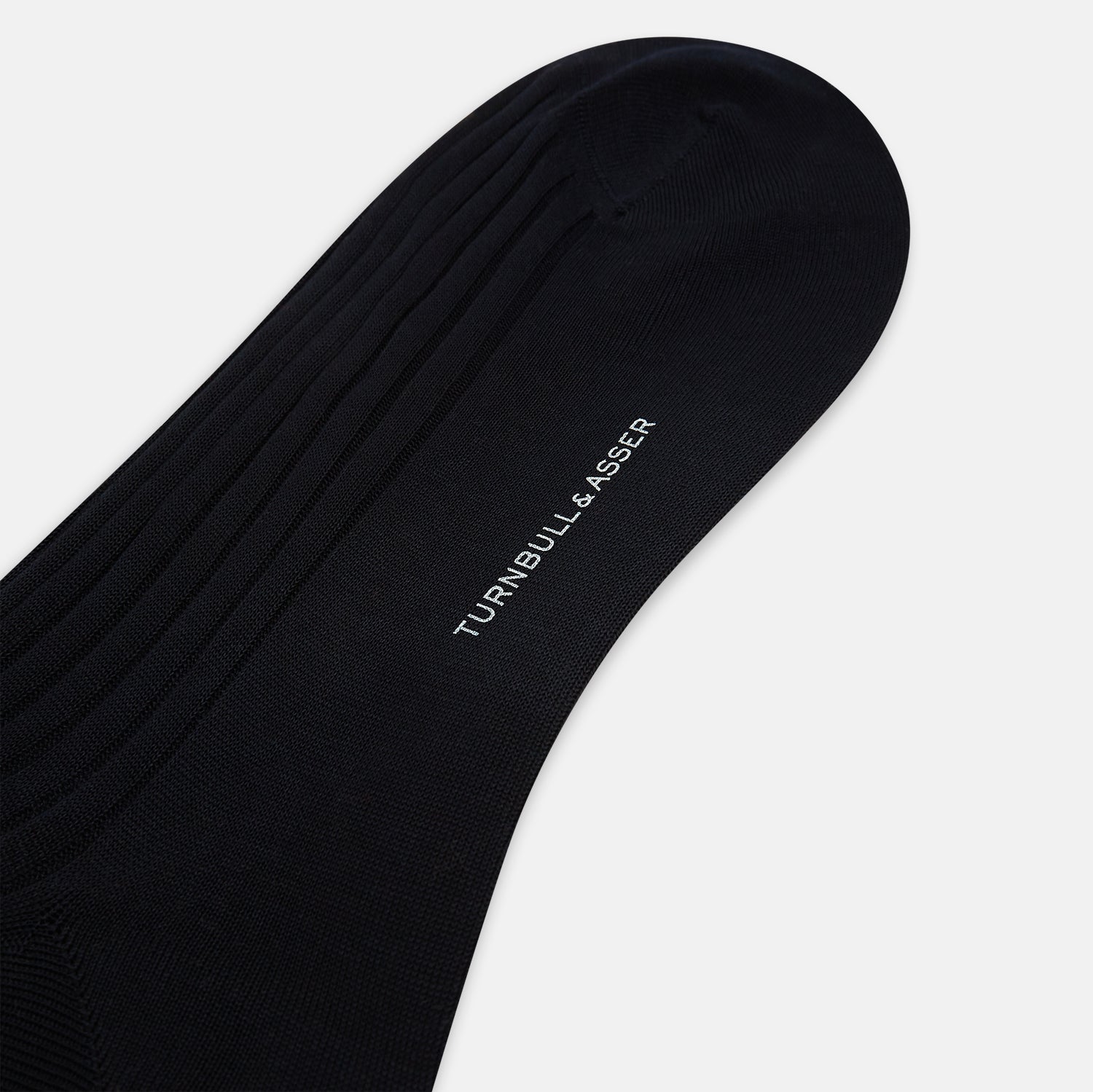 View 3 of product A single Midnight Blue Long Sock by Turnbull & Asser is shown on a white background, showcasing a ribbed texture and a fitted design that extends from the foot to the top of the calf.