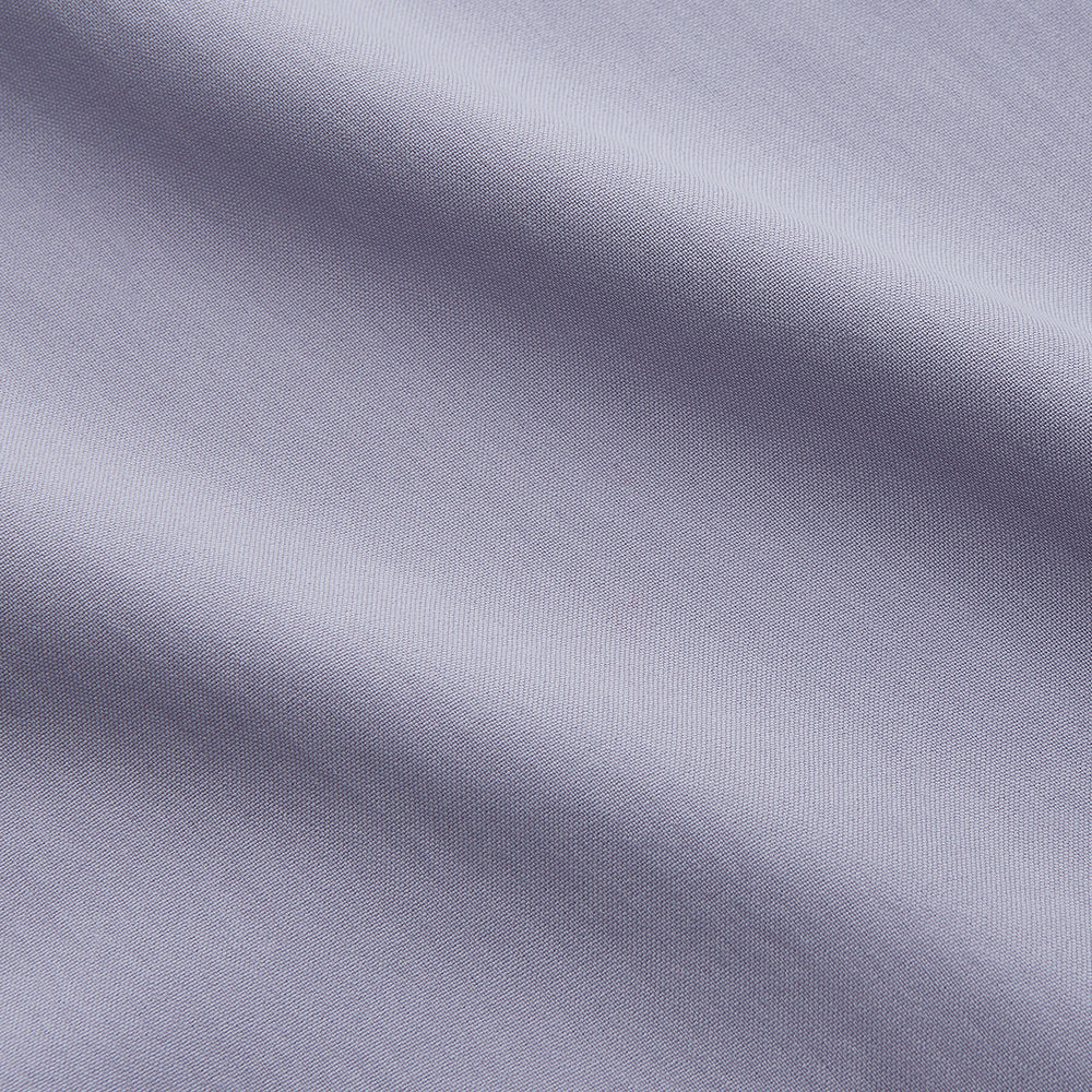 The Turnbull & Asser Lilac Silk Regular Fit Flaxton Shirt features long sleeves, a classic collar, white buttons, and a curved hem, shown laid flat on a white background.