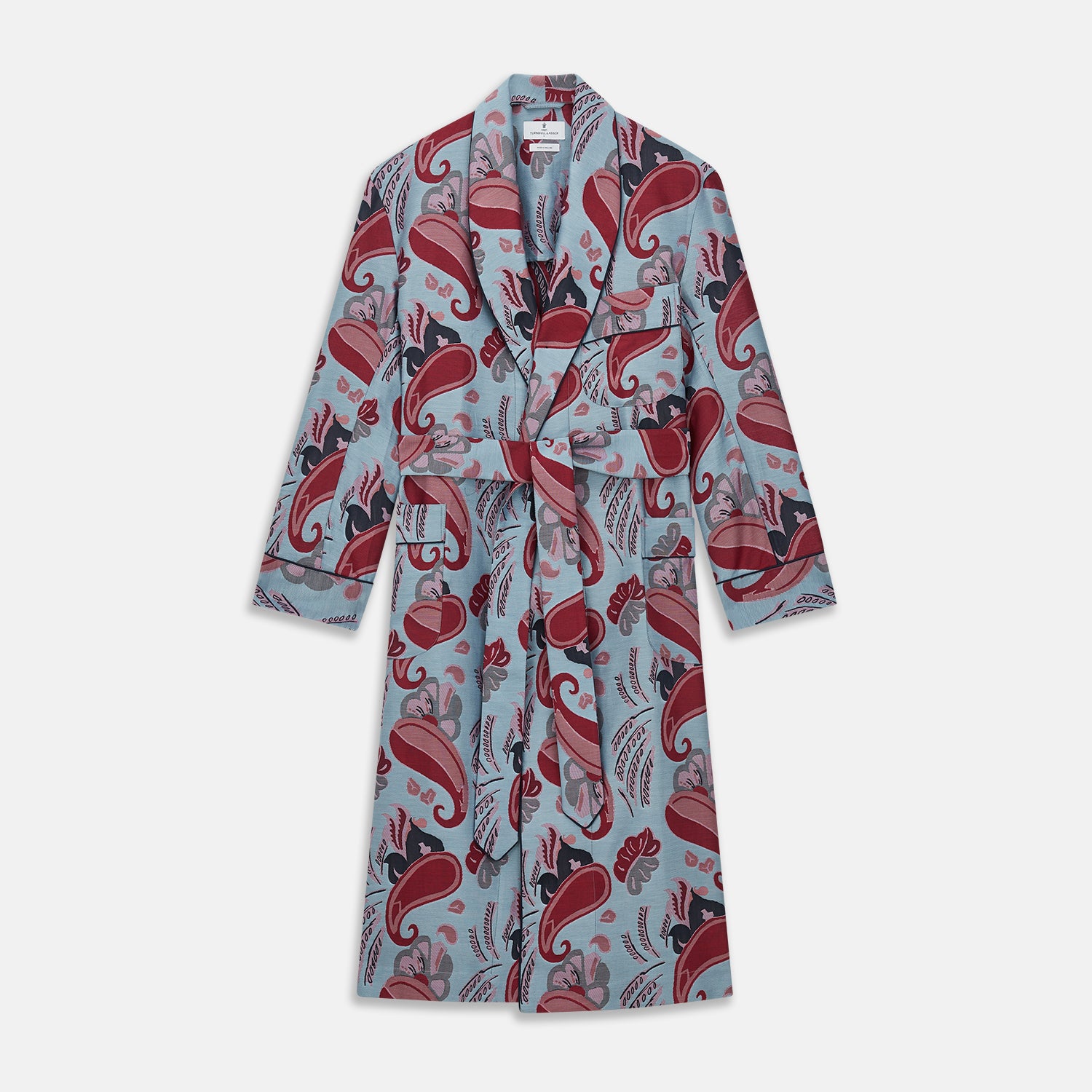 View 1 of product The Blue Paisley Pattern Cotton Arnold Gown by Turnbull & Asser features light blue jacquard cotton with a red and black paisley design, long sleeves, a matching belt, and two front pockets for a subtle Bloomsbury-inspired look.