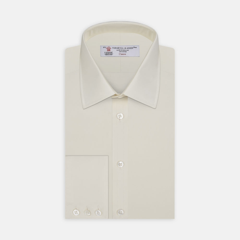 A close-up of Turnbull & Asser's Cream Cotton Fabric, framed by a circular gray border. The smooth cotton shows a subtle seam on the right, highlighting the product's fine texture and quality.