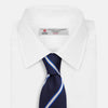 View 2 of product The White and Navy Blazer Silk Tie by Turnbull & Asser features diagonal white and light blue stripes on navy silk, shown rolled on a white background. A refined choice to complement any office shirt.