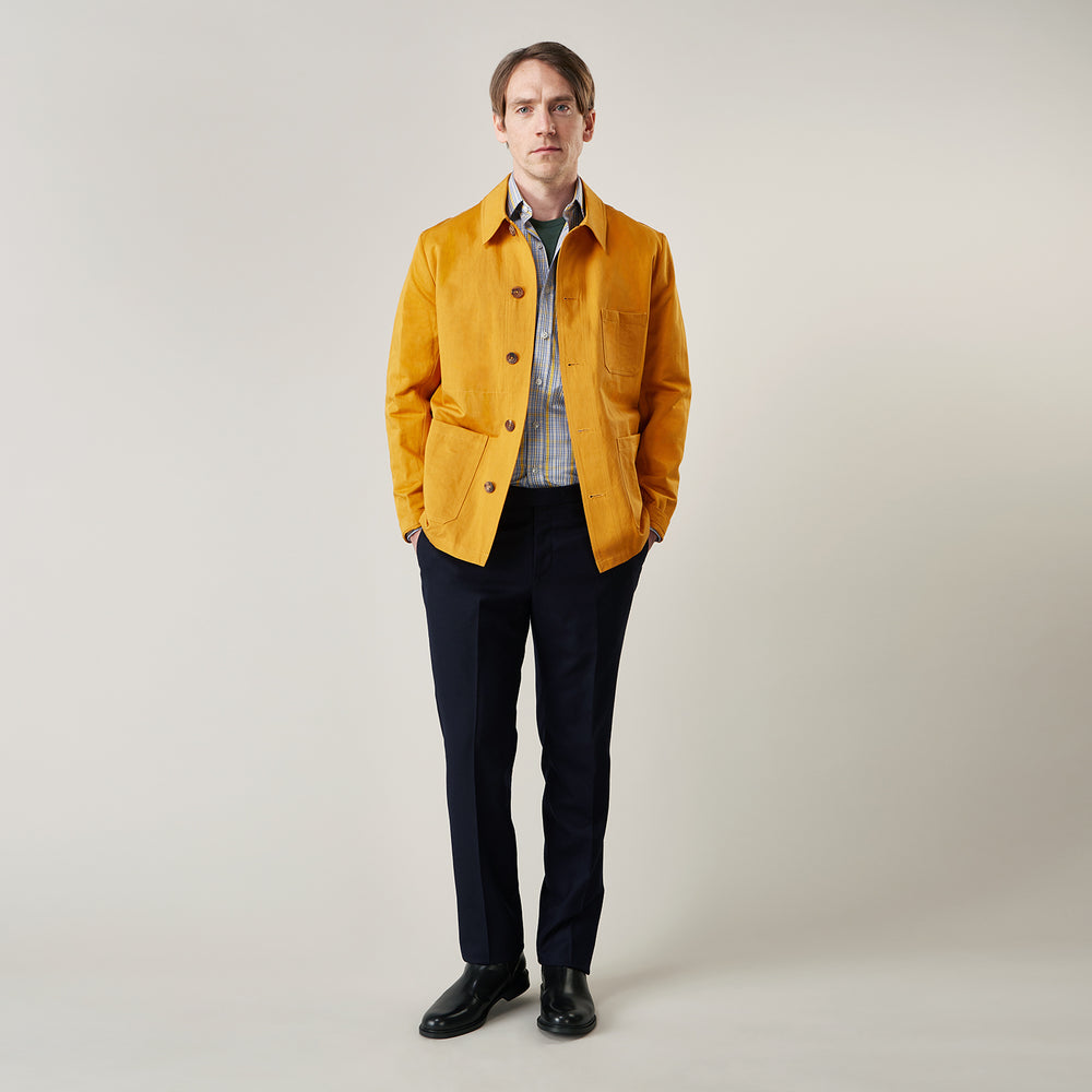The Turnbull & Asser Ochre Cotton-Linen Remy Chore Jacket features a collar, long sleeves, brown front buttons, and three patch pockets, shown on a plain white background.