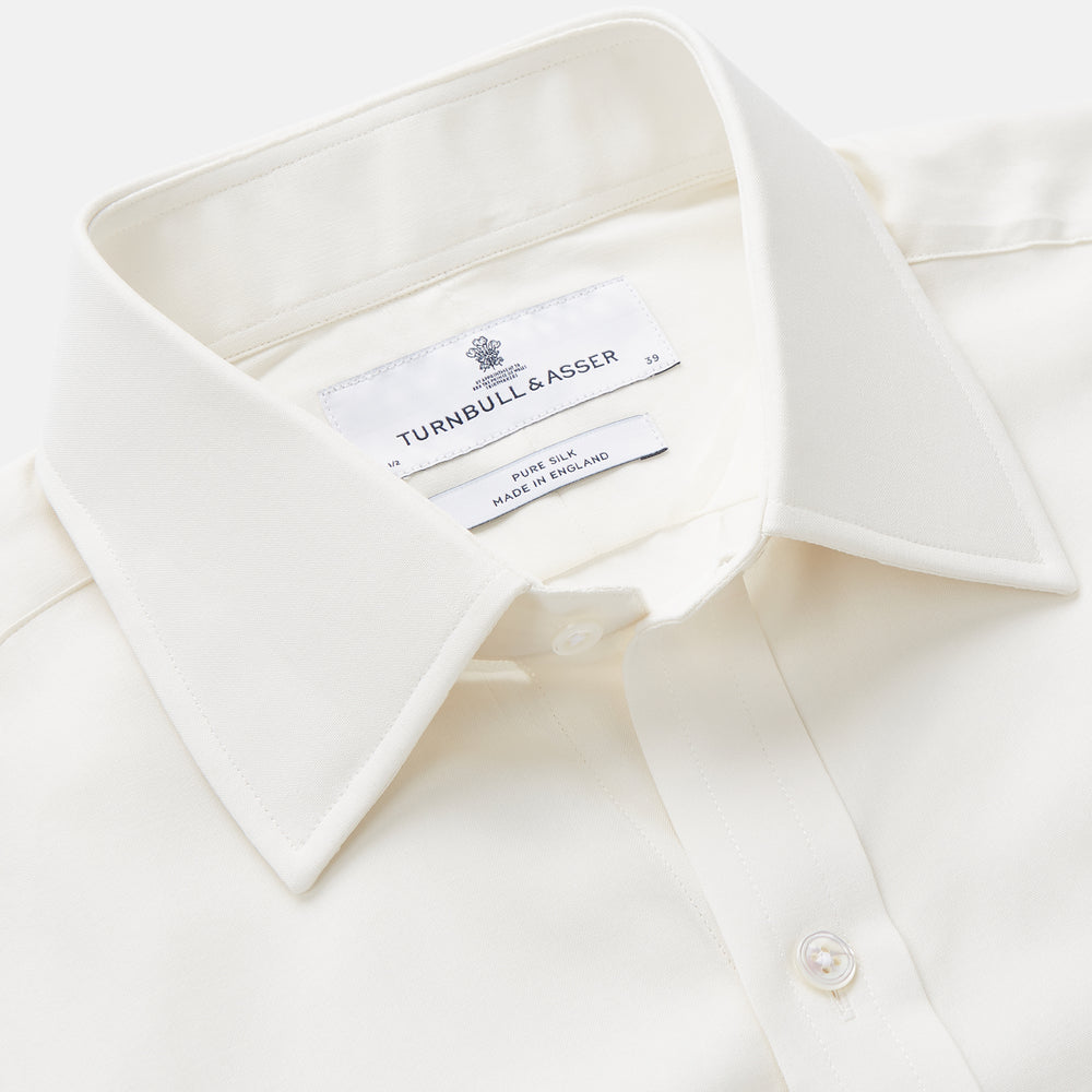 The Cream Silk Whitby Shirt by Turnbull & Asser features a pointed collar, buttoned front and cuffs, and long sleeves, shown in Whitby Fit and laid flat on a white background.