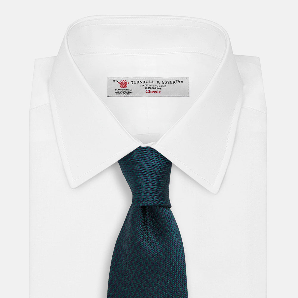 The Turnbull & Asser Navy Houndstooth Forest Green Tie is shown rolled up, featuring a subtle houndstooth pattern against a plain white background.