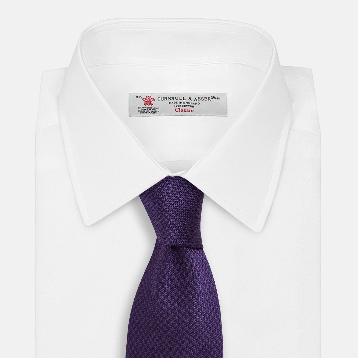 View 2 of product The HOUNDSTOOTH NAVY PLUM TIE by Turnbull & Asser, featuring a textured pattern, is showcased rolled up against a plain white background—an essential accessory.