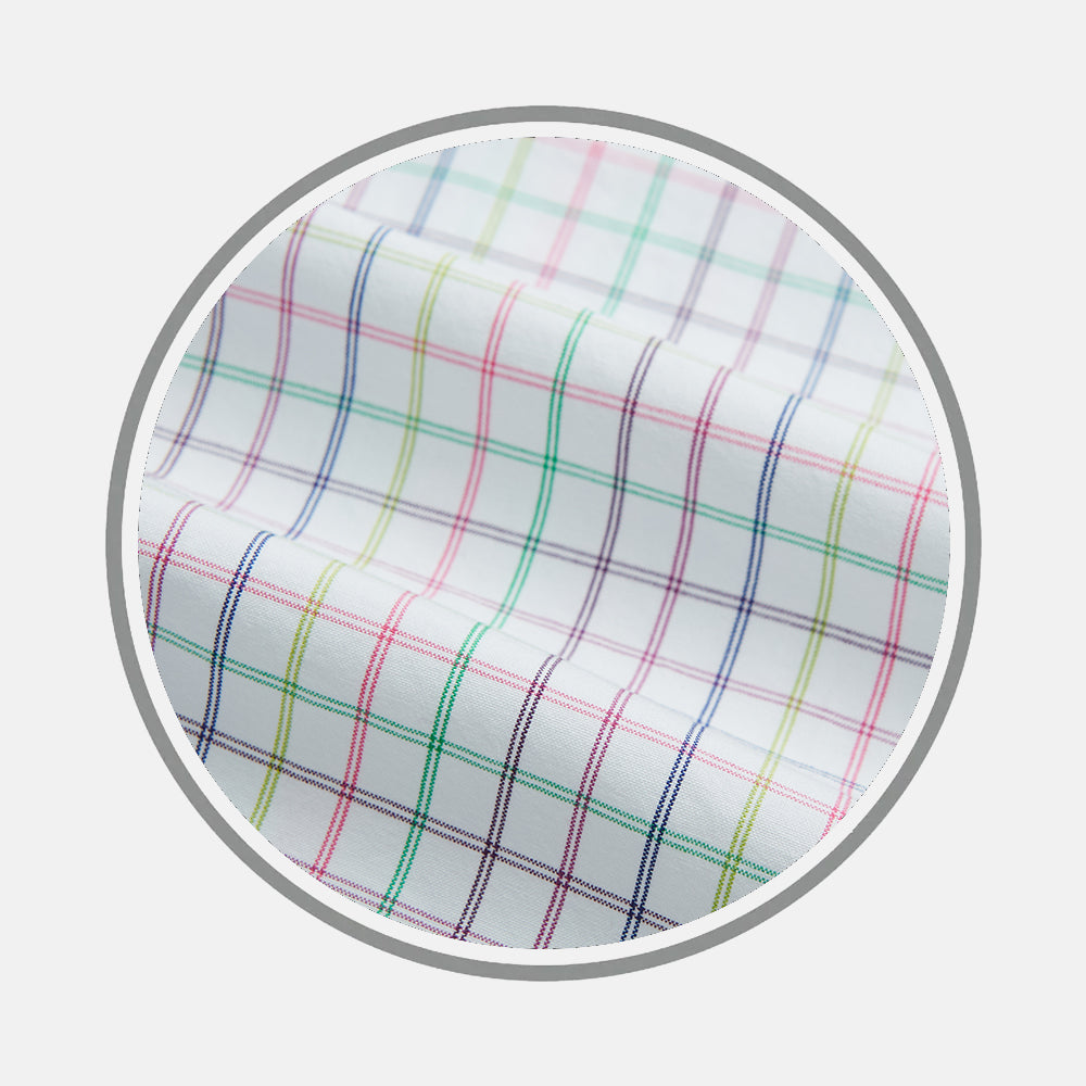A close-up of Turnbull & Asser's MULTICOLOURED DOUBLE GRID CHECK FABRIC shows soft white fabric with thin red, blue, green, yellow, and purple lines in a plaid pattern, slightly wrinkled within a circular frame.
