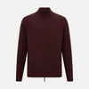 View 1 of product The Turnbull & Asser Burgundy Merino High Neck Zipped Cardigan features long sleeves, a zip-up front, and ribbed collar, cuffs, and hem, crafted from soft merino knitwear and shown on a white background.