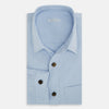 View 5 of product The Turnbull & Asser Pale Blue Hyde Overshirt is a long-sleeve, sanforised cotton button-up with a single chest pocket and dark buttons, shown on a plain white background.