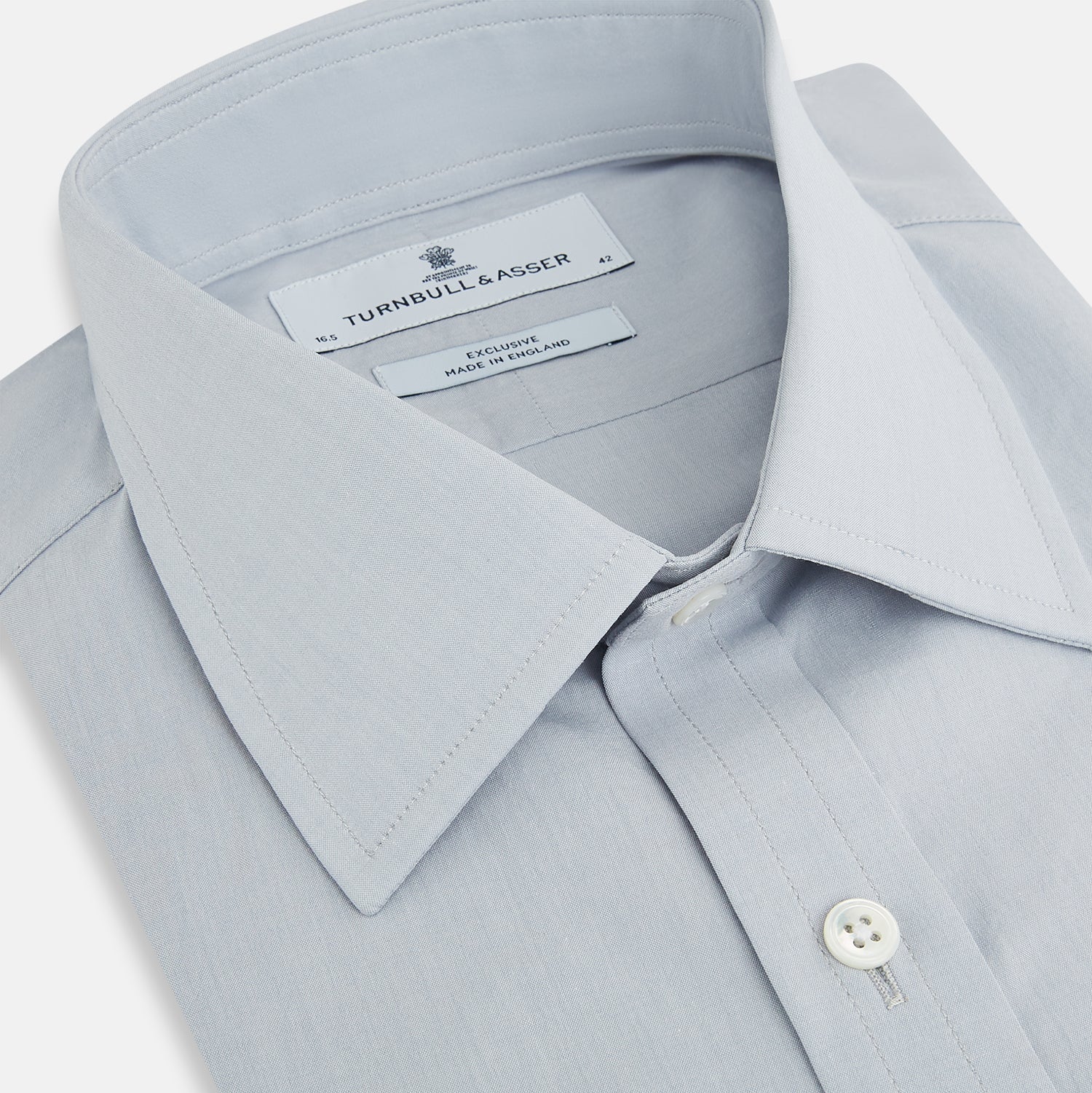 View 2 of product The Dove Grey Mayfair Shirt by Turnbull & Asser is a long-sleeve button-up with a collar, front pocket, and white buttons, crafted from soft sanforised cotton and laid flat on a white background.