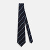 View 2 of product The Turnbull & Asser Navy Broken Shadow Stripe Silk Tie features British excellence with a light blue and white zigzag pattern and is shown rolled up on a plain white background.