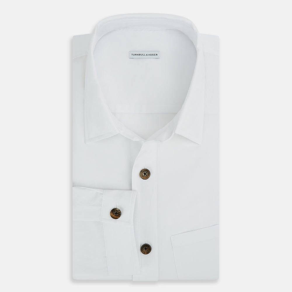 The White Hyde Overshirt by Turnbull & Asser is crafted from sanforised cotton with a left chest pocket and dark buttons—offering a sharp, casual blazer alternative. Shown laid flat on a white background.