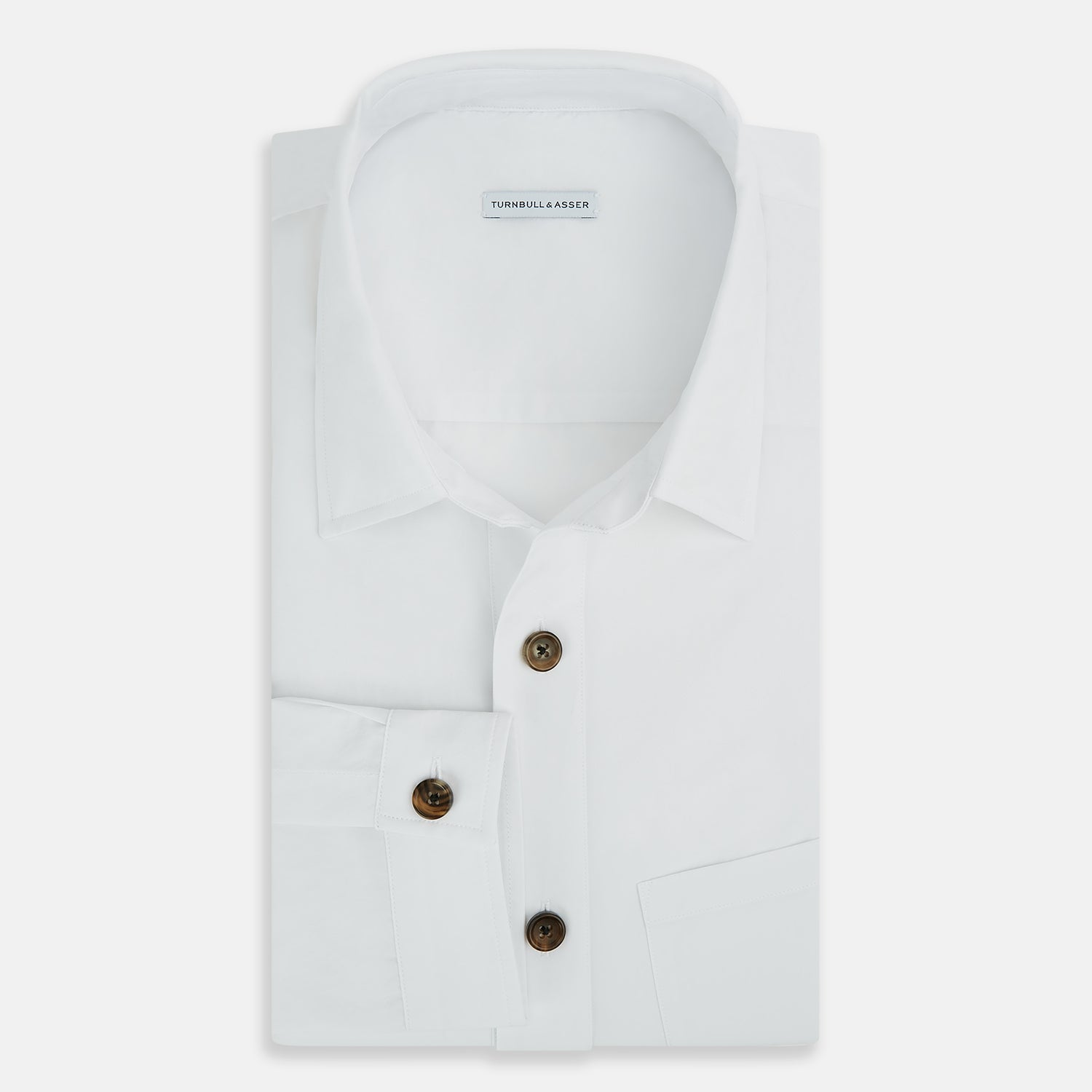 View 5 of product The White Hyde Overshirt by Turnbull & Asser is crafted from sanforised cotton with a left chest pocket and dark buttons—offering a sharp, casual blazer alternative. Shown laid flat on a white background.