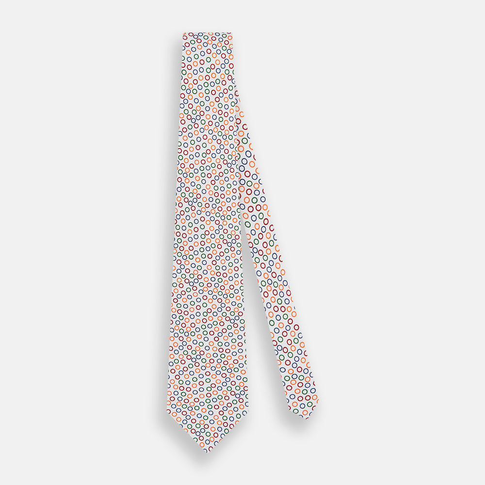 The Turnbull & Asser Confetti Circle White Silk Tie features colorful rings in red, orange, blue, and green scattered across a crisp white background.