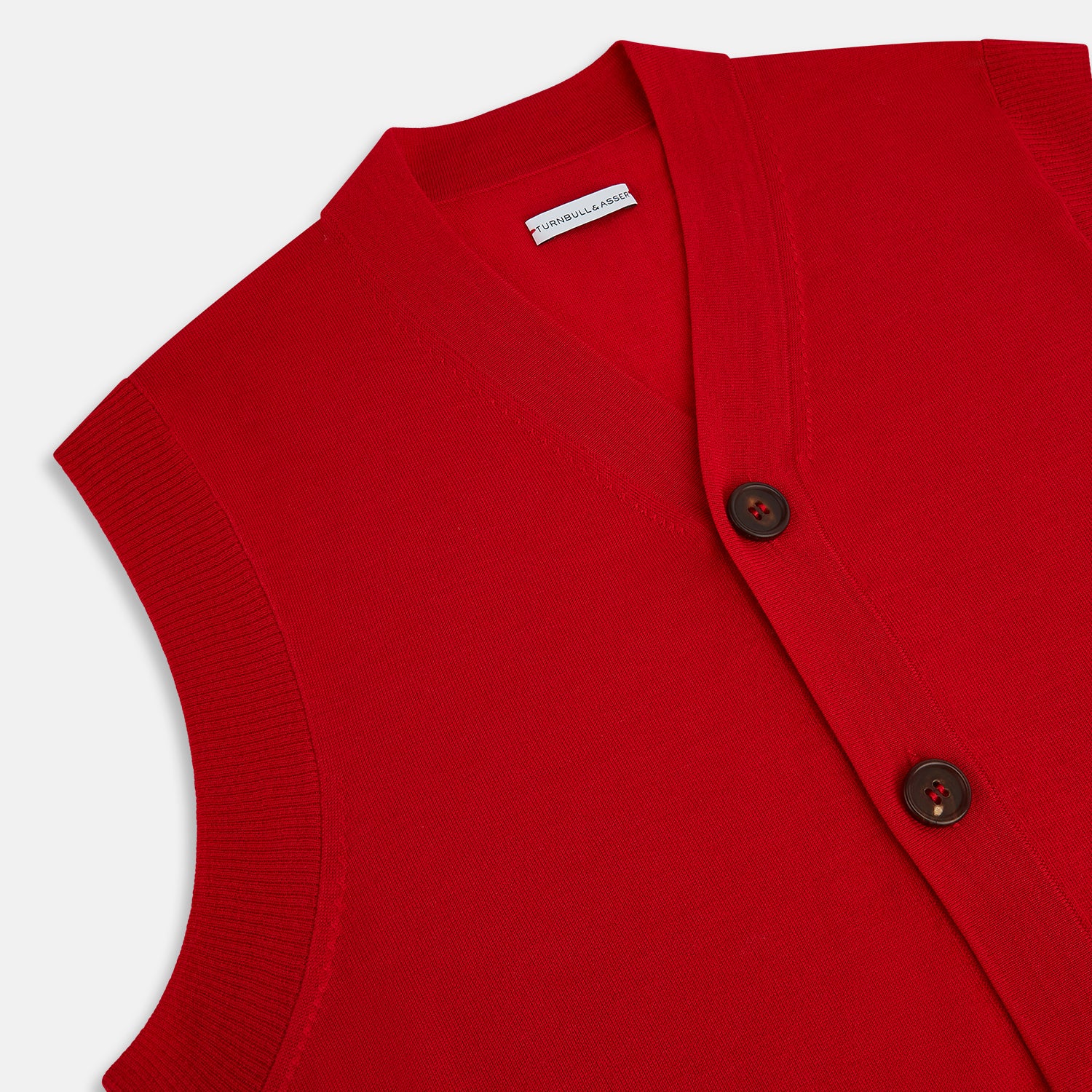 View 2 of product The Turnbull & Asser Red Fine Merino V-Neck Sleeveless Cardigan features a collarless neckline, two front pockets, and five dark buttons, shown on a plain white background.