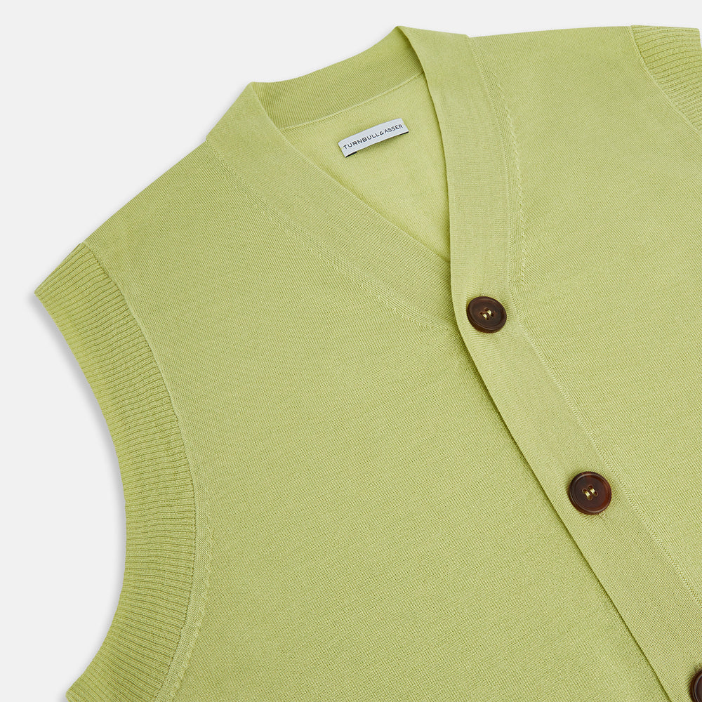 The Melon Green Fine Merino V-Neck Sleeveless Cardigan by Turnbull & Asser features a ribbed collar, five dark brown buttons, and two front pockets—adding sophisticated style to any ensemble, shown against a plain white background.