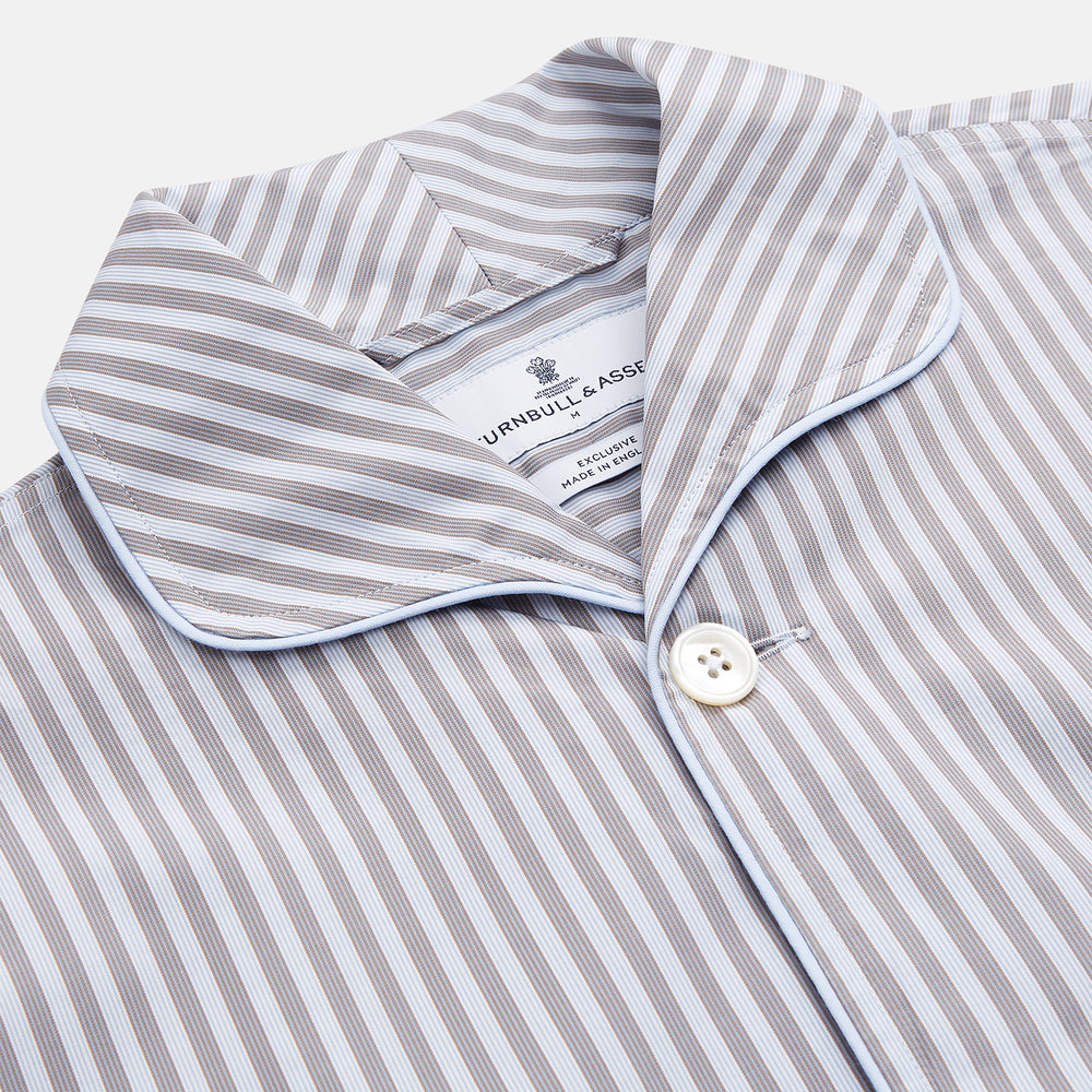 The Turnbull & Asser Pale Blue Multi Stripe Cotton Quin Pyjamas, featuring a long-sleeve button-up top and matching adjustable tie-waist pants, are neatly arranged on a white background.