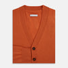 View 4 of product The Orange Cashmere Cardigan by Turnbull & Asser showcases vibrant burnt orange, a V-neck, dark buttons, ribbed cuffs and hem, long sleeves, and two front pockets. Part of the knitwear collection; displayed on a white background.