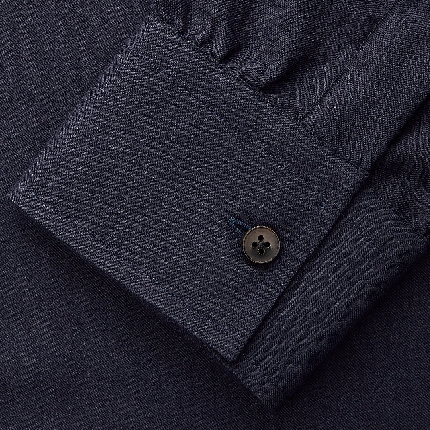 View 6 of product A man stands against a beige background wearing the Turnbull & Asser Navy Weekend Fit Cotton & Wool Shirt with a Derby collar and 1 button cuffs, paired with brown pants and black shoes, looking to the side with a neutral expression.