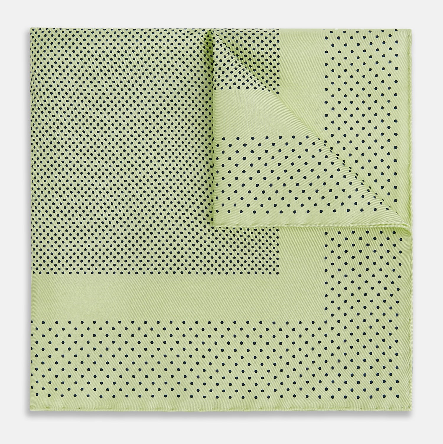 View 1 of product The Melon Green Dot Silk Pocket Square by Turnbull & Asser is handmade in England from silk, featuring small black polka dots. Shown folded with a turned-up corner, it displays both sides of the light green fabric.