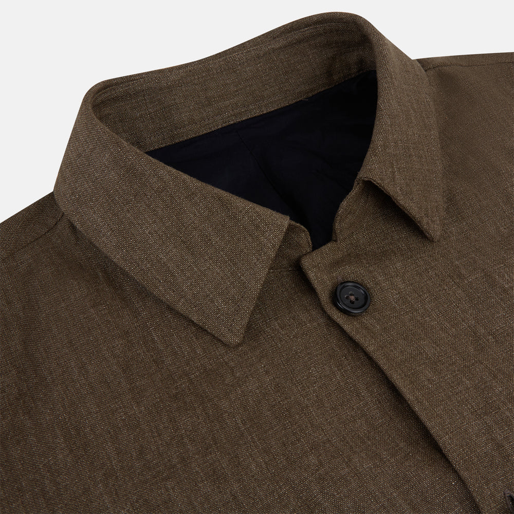 The Pine Cone Linen Holland Shacket by Turnbull & Asser is a brown men's lightweight outerwear piece with a collar, long sleeves, three front zip pockets, and black buttons, shown on a white background.