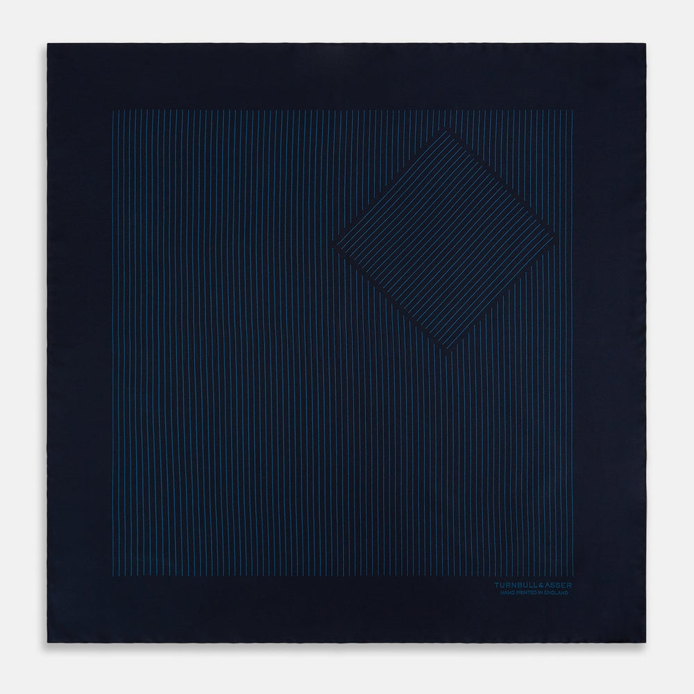 The Navy and Blue Stripe Silk Pocket Square by Turnbull & Asser features vertical blue pinstripes, is crafted from silk with hand-rolled edges, and is finished with the brand's logo printed in blue at the lower right corner.