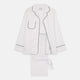 The Turnbull & Asser Women's Harriet Plain White Cotton Pyjama Set features long sleeves, black piping, a chest pocket, and matching pants with elastic waistband and ribbon tie, all displayed on a white background.