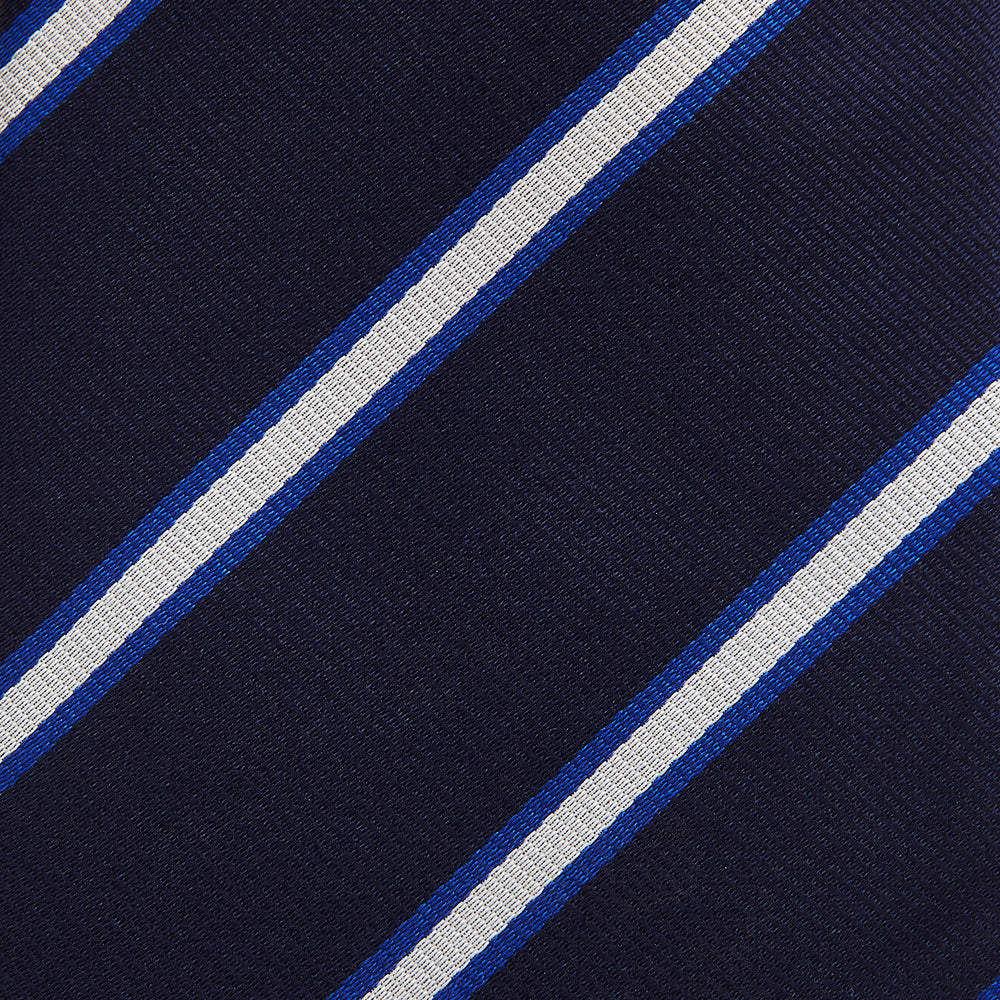 The White and Navy Blazer Silk Tie by Turnbull & Asser features diagonal white and light blue stripes on navy silk, shown rolled on a white background. A refined choice to complement any office shirt.