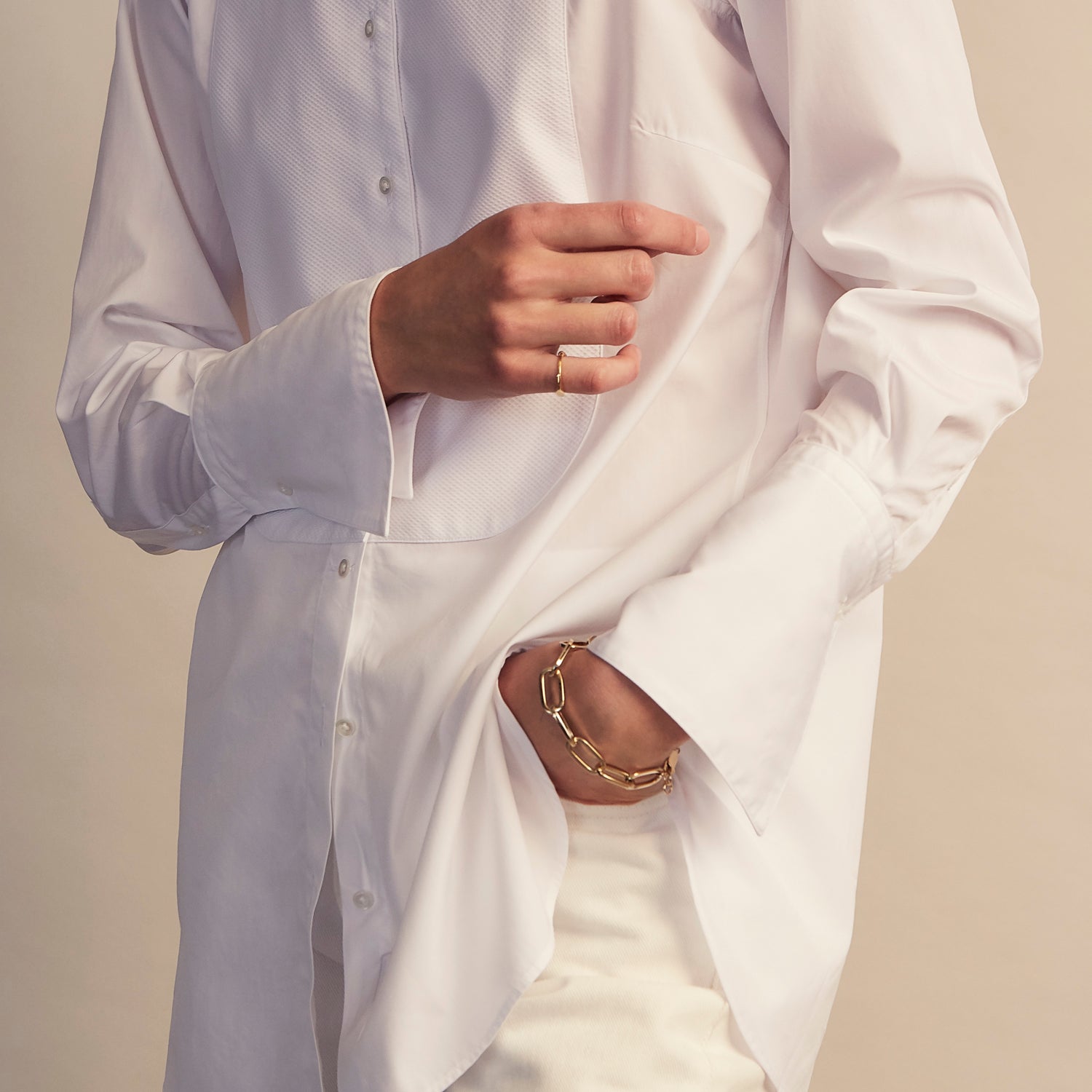 View 6 of product A person with curly hair wears the Turnbull and The Deck White Cotton Minimalist Shirt by Turnbull & Asser, paired with pants. Posed against a plain background, their minimalist silhouette is highlighted in this black and white image.