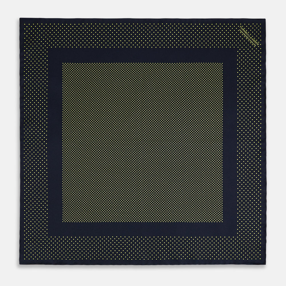 The Turnbull & Asser Navy and Yellow Dot Silk Pocket Square features a navy base with yellow dots, a solid navy border, and a folded corner showing the patterned underside for an elegant accent.