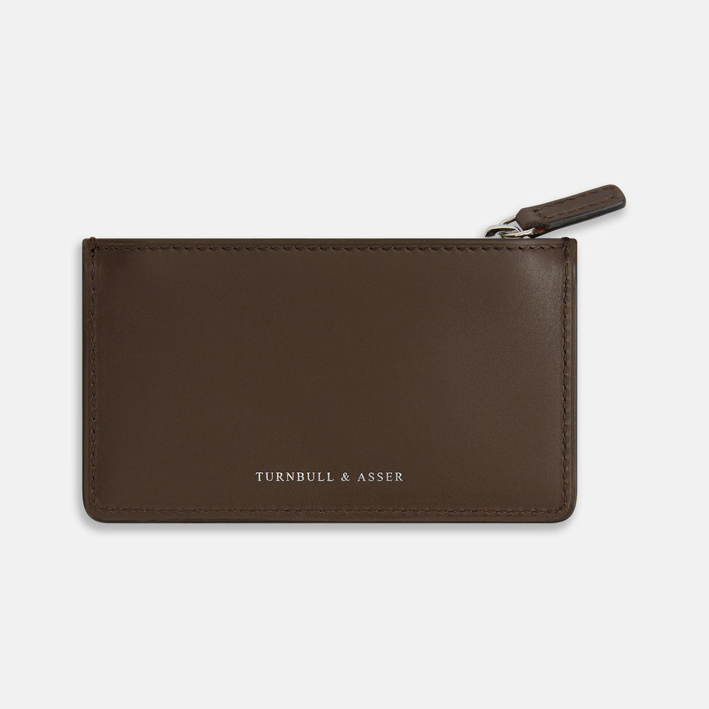 The Dark Chocolate Leather Zip Wallet by Turnbull & Asser, crafted from full-grain Italian leather, features a white brand logo on the front and is displayed against a plain white background.