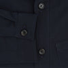 View 4 of product The Midnight Blue Hyde Overshirt by Turnbull & Asser is a plain, long-sleeve shirt in dark navy sanforised cotton with a single chest pocket, spread collar, and black buttons, shown laid flat on a white background.