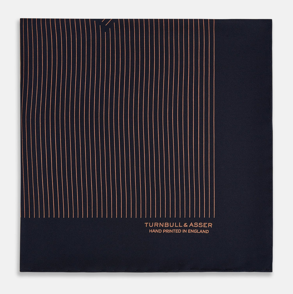The Turnbull & Asser Navy and Blush Stripe Silk Pocket Square features thin blush stripes on navy silk, finished with "TURNBULL & ASSER HAND PRINTED IN ENGLAND" in the corner, highlighting its refined English craftsmanship.