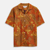 View 1 of product The Orange & Ochre Tapestry Weave Cotton Holiday Fit Shirt by Turnbull & Asser is a short-sleeve, revere collar shirt featuring a yellow and brown floral and leaf pattern on an orange base, finished with white buttons.
