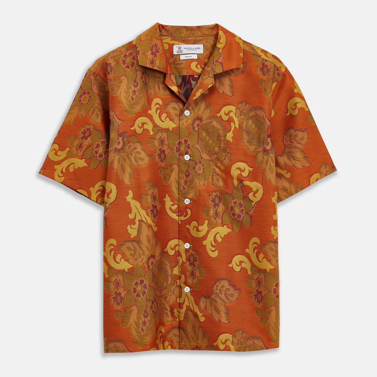 View 1 of product The Orange & Ochre Tapestry Weave Cotton Holiday Fit Shirt by Turnbull & Asser is a short-sleeve, revere collar shirt featuring a yellow and brown floral and leaf pattern on an orange base, finished with white buttons.