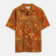 The Orange & Ochre Tapestry Weave Cotton Holiday Fit Shirt by Turnbull & Asser is a short-sleeve, revere collar shirt featuring a yellow and brown floral and leaf pattern on an orange base, finished with white buttons.