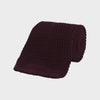 View 1 of product The Turnbull & Asser MTIE011-ZAI003 TIES 7.5CM is a plain burgundy tie shown rolled on a white background, featuring straight edges and textured knit—ideal for the modern gentleman’s versatile wardrobe.