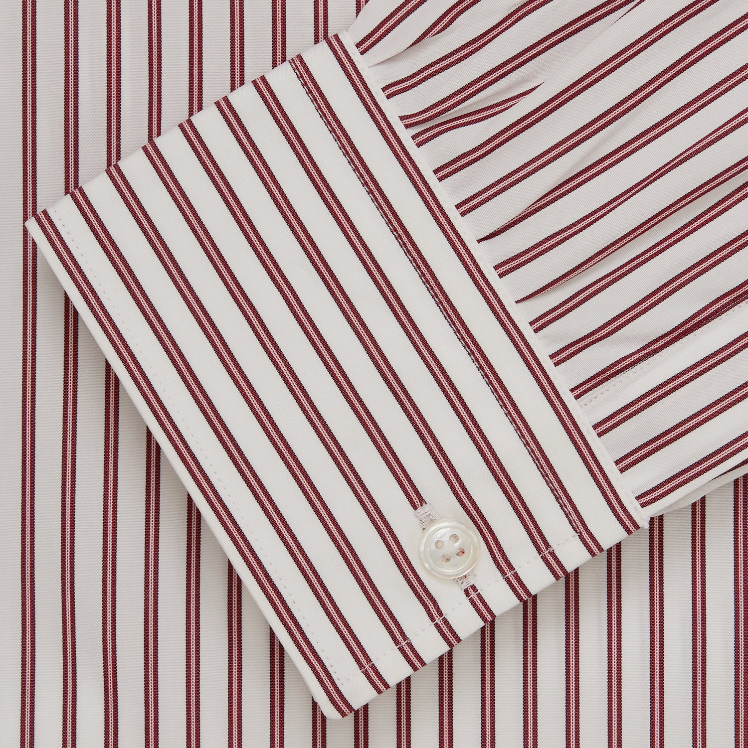 View 5 of product The Turnbull & Asser Burgundy Stripe Weekend Fit Shirt features a Derby collar, 1-button cuffs, and vertical burgundy and white stripes, shown laid flat on a plain light background.