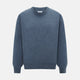 The Turnbull & Asser Pacific Blue Cashmere Round Neck Jumper features long sleeves and ribbed cuffs, hem, and neckline, shown on a light grey background.