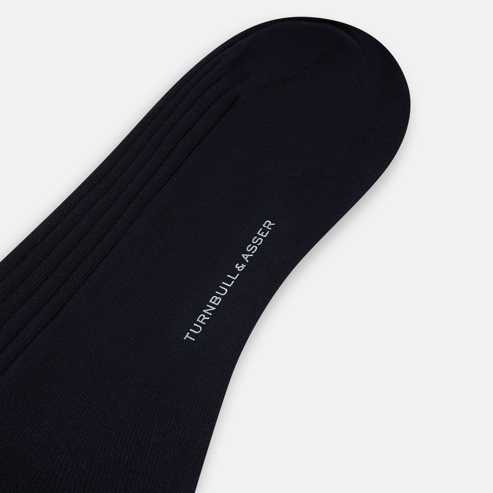 A single navy mid-length sock by Turnbull & Asser, crafted from organic cotton with a ribbed texture, stands upright on a white background.